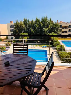 a wooden table and chairs on a balcony with a pool at Apartamento golf-mar in Vilamoura