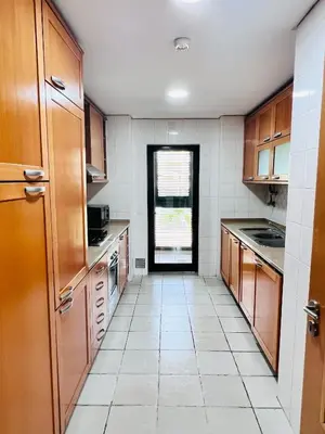 a kitchen with wooden cabinets and a white tile floor at Apartamento golf-mar in Vilamoura
