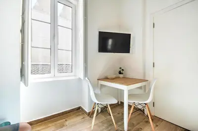 a small table and two chairs in a room with a window at Blue Barqueta Studio in Faro