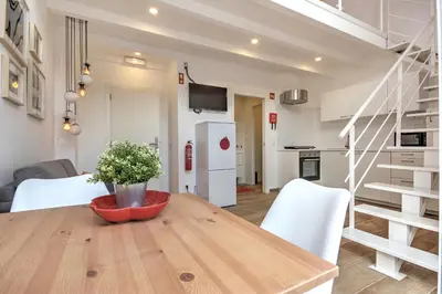 a kitchen and dining room with a wooden table and white appliances at Terrace Barqueta Studio in Faro