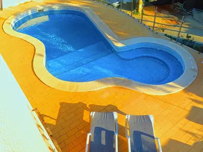 a swimming pool with two chairs next to it at Villa Esmeralda in Albufeira