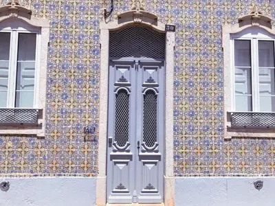 a gray door on a building with a tile wall at Yellow Barqueta Studio in Faro