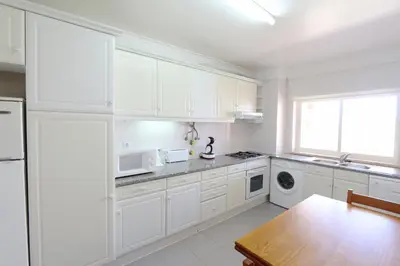 a white kitchen with white cabinets and a table at Indico 154 - Clever Details in Vilamoura