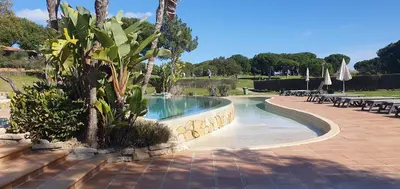 a pool at a resort with palm trees and chairs at Apt P209 situé au sein de Balaia Golf Village in Albufeira