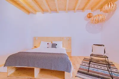 a white bedroom with a bed and a chair at A Casa D'Amelie in Faro