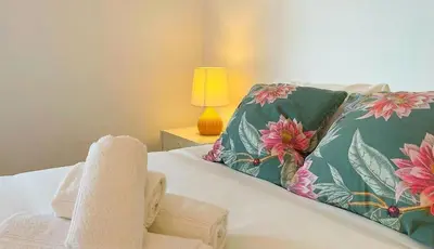 a bedroom with a bed with towels and a lamp at Ria Beach House in Faro