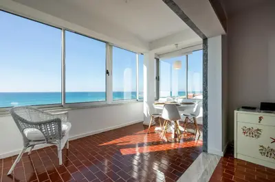 a living room with a table and chairs and the ocean at Ria Beach House in Faro