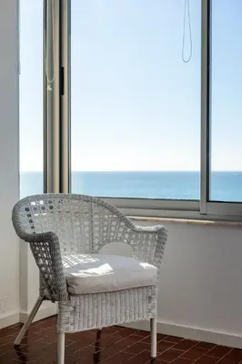 a wicker chair sitting in front of a window at Ria Beach House in Faro