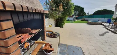 a barbecue grill with food on it next to a patio at Villa Margarida by Laranjal Rentals in Albufeira