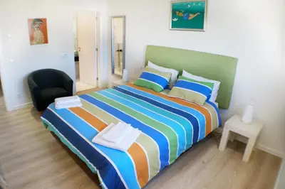 a bedroom with a large bed and a chair at Villa Margarida by Laranjal Rentals in Albufeira