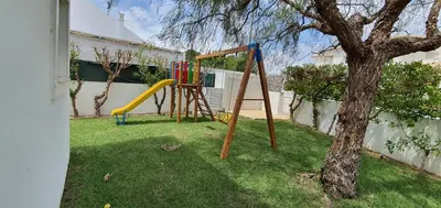 a playground in a yard next to a tree at Sunset Villa by Laranjal Rentals in Olhos de Água
