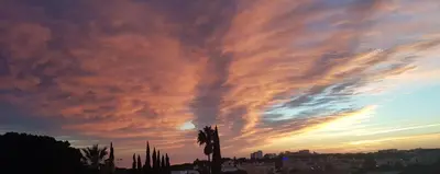a cloudy sky at sunset with a palm tree at Sunset Villa by Laranjal Rentals in Olhos de Água