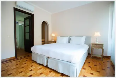 a large white bed in a room with a wooden floor at Senhor Gigi in Faro