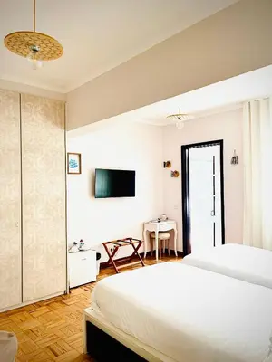 a white bedroom with a bed and a television at Senhor Gigi in Faro