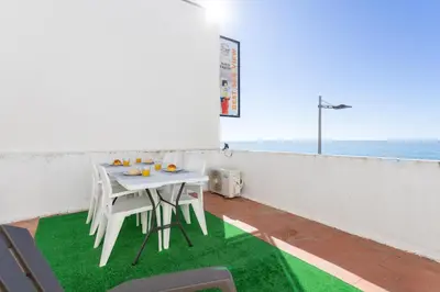 a white table and chairs on a balcony with the ocean at #003 Cottage By Home Holidays in Albufeira