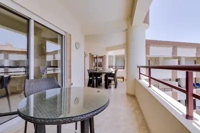 a balcony with a glass table and a dining room at Avelãs - Modern apartment - Vilamoura in Vilamoura