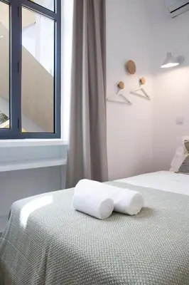 a white bedroom with a bed with a towel on it at Alameda Exclusive House in Faro