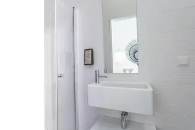 a white bathroom with a sink and a mirror at Alameda Exclusive House in Faro