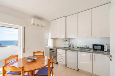 a kitchen with white cabinets and a table with chairs at Edifício Sequeira - Alojamento Local by Umbral in Albufeira