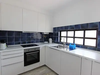 a kitchen with white cabinets and a sink and a window at Albufeira Apartments in Albufeira