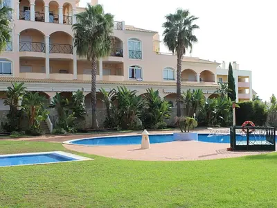 a large apartment building with a swimming pool and palm trees at Los Arcos Apartment I in Vilamoura