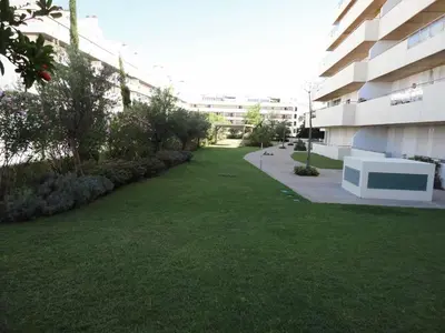 a grassy yard next to a building with a building at Marina Vilamoura - Aquamar 209 - By Vilamoura Sun in Vilamoura
