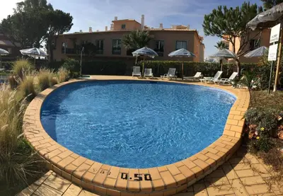a swimming pool in a yard with chairs and umbrellas at Excelente T1 Oura Beach Bicos Apartment Lucia in Albufeira