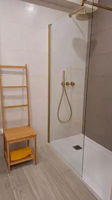 a shower with a glass door and a wooden chair at The Market Square House in Faro