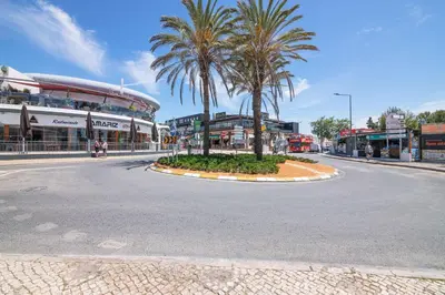 an empty street with palm trees in the middle at Beti Oura Village in Albufeira