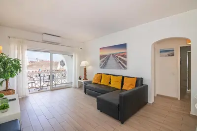 a living room with a couch and a balcony at Beti Oura Village in Albufeira