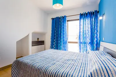 a bedroom with a bed with blue curtains and a window at ★ Sea View ★ 1 Minute to Oldtown and Beach ★ in Albufeira