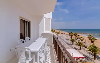 a balcony with a white table and chairs and the beach at Atlântico View - Beach front - Quarteira in Quarteira