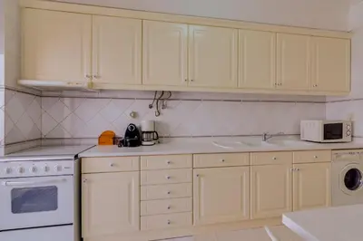 a kitchen with white cabinets and a white microwave at Atlântico View - Beach front - Quarteira in Quarteira