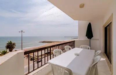 a balcony with a white table and chairs and the ocean at Atlântico View - Beach front - Quarteira in Quarteira