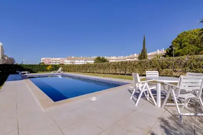 a patio with a table and chairs next to a swimming pool at Ribas - Cozy 2 bedroom apartment - Vilamoura in Vilamoura