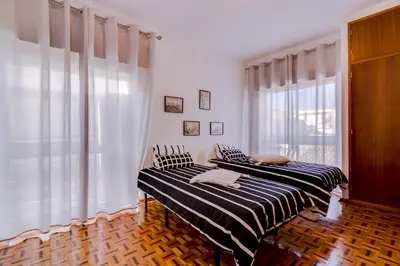 two beds in a room with white walls and windows at Casa da Esquina - Faro city center in Faro