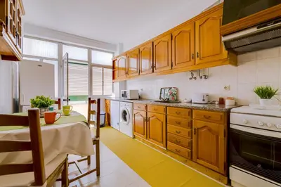a kitchen with wooden cabinets and a table and a dining room at Casa da Esquina - Faro city center in Faro