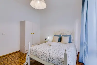 a bedroom with a white bed with blue pillows at Casa da Esquina - Faro city center in Faro
