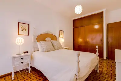 a bedroom with a white bed and a wooden door at Casa da Esquina - Faro city center in Faro