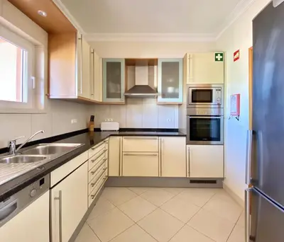 a kitchen with white cabinets and a stainless steel refrigerator at Amazing 2Bedroom apartment in Victoria Boulevard in Vilamoura