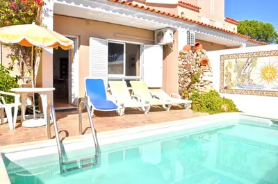 a swimming pool with two lounge chairs and a table at Stylish and well-equipped, private pool, close to amenities, free AC and Wifi in Quarteira