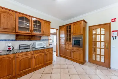 a large kitchen with wooden cabinets and a doorway at Quinta das Laranjeiras in Boliqueime