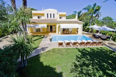 a villa with a swimming pool in front of a house at Villa Jasmim in Almancil