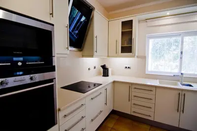 a kitchen with white cabinets and a black appliance at Villa Jasmim in Almancil