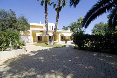 a house with palm trees in front of a driveway at Villa Jasmim in Almancil