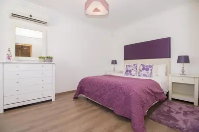 a bed with purple and white pillows on it at Villa Magali in Galé
