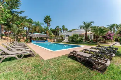 a swimming pool with lounge chairs and a house at Villa Natura in Vilamoura