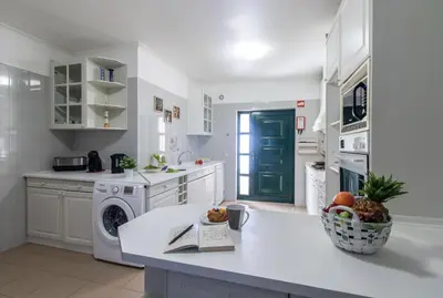 a white kitchen with a sink and a dishwasher at Casa Clara in Vilamoura