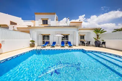 a villa with a swimming pool in front of a house at Villa Chiquito Albufeira - Private Pool&Parking - BBQ&AC&WI-FI in Albufeira