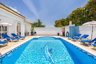 a swimming pool with blue chairs and a house at Villa Chiquito Albufeira - Private Pool&Parking - BBQ&AC&WI-FI in Albufeira